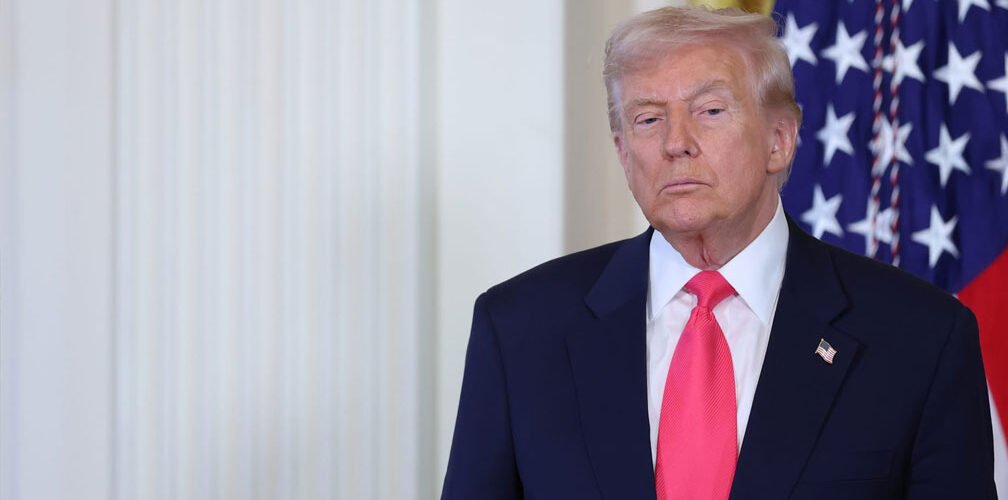 الرئيس الأميركي دونالد ترامب خلال ظهور إعلامي على خلفية العلم الأميركي 