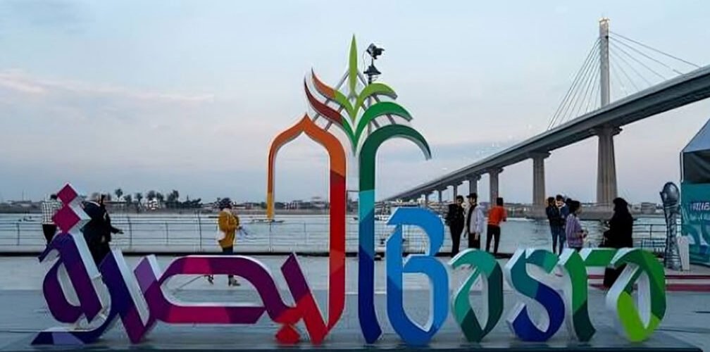 لافتة البصرة على كورنيش شط العرب في مدينة البصرة مع جسر البصرة المعلق في الخلفية