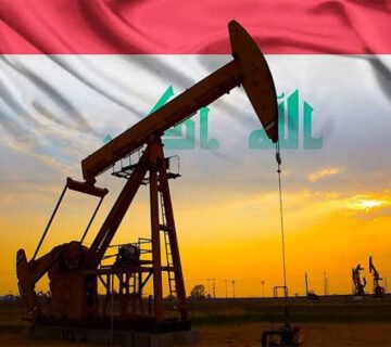 مضخة نفط تعمل في أحد حقول النفط العراقية مع علم العراق في الخلفية