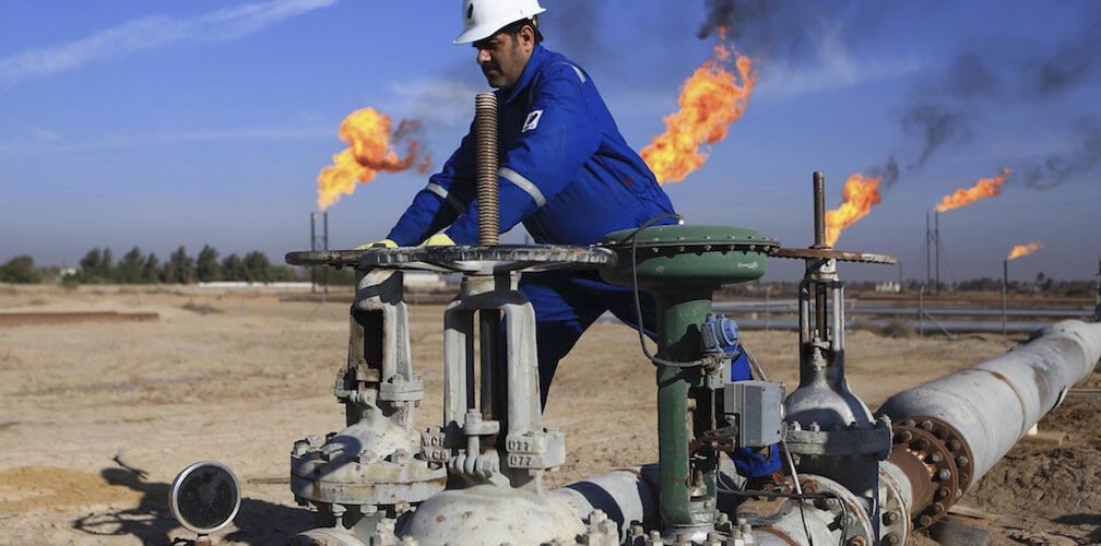 عامل في حقل نفطي عراقي مع أنابيب استخراج النفط