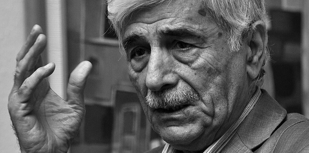 صورة بالأبيض والأسود للشاعر العراقي كاظم الحجاج أثناء حديثه في لقاء ثقافي 