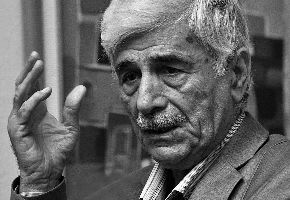 صورة بالأبيض والأسود للشاعر العراقي كاظم الحجاج أثناء حديثه في لقاء ثقافي 