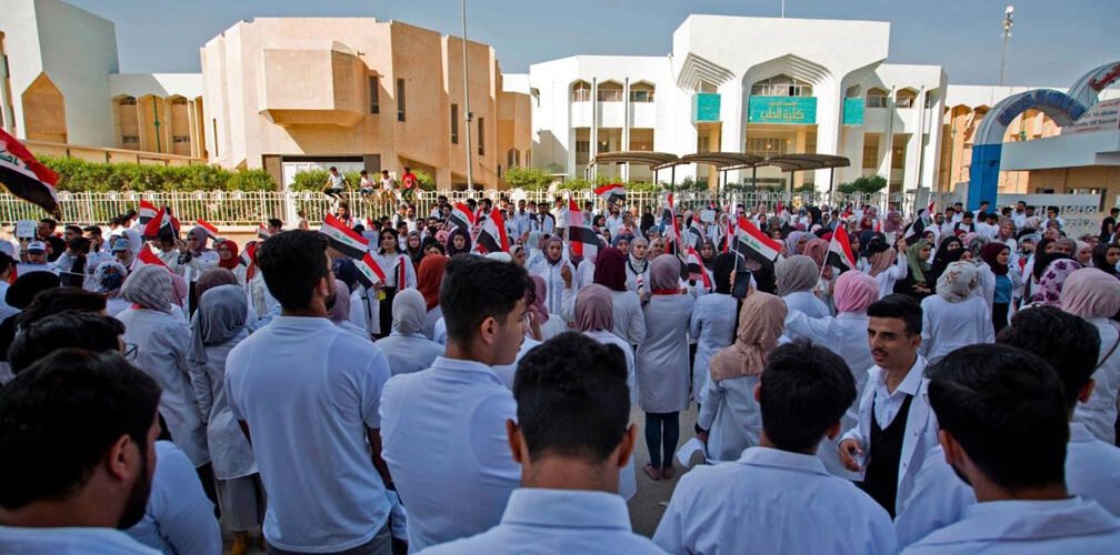 طلبة كلية الطب بجامعة البصرة يرتدون المعاطف البيضاء ويرفعون الأعلام العراقية أمام مباني الكلية 