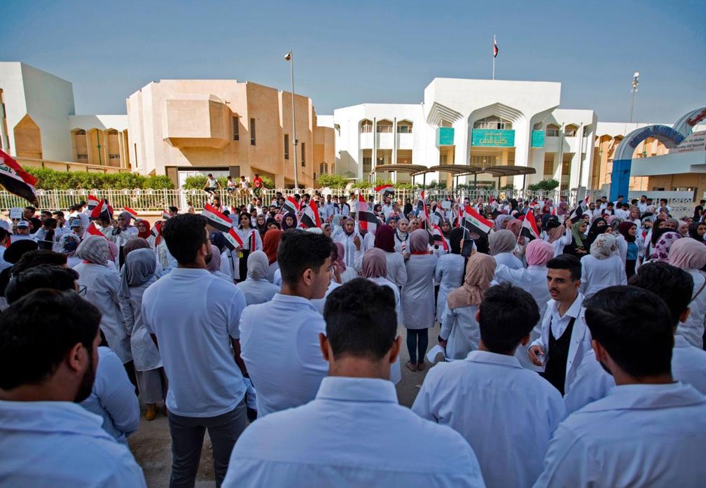 طلبة كلية الطب بجامعة البصرة يرتدون المعاطف البيضاء ويرفعون الأعلام العراقية أمام مباني الكلية 