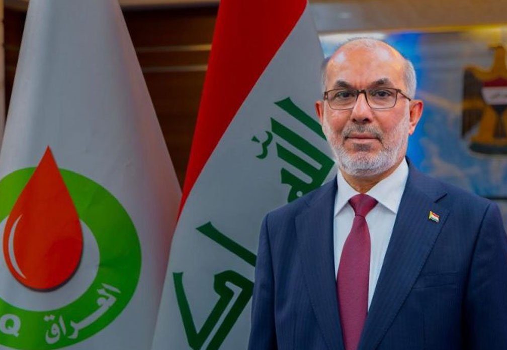 وزير النفط العراقي باسم خضير العبادي يقف أمام العلم العراقي وشعار وزارة النفط العراقية 